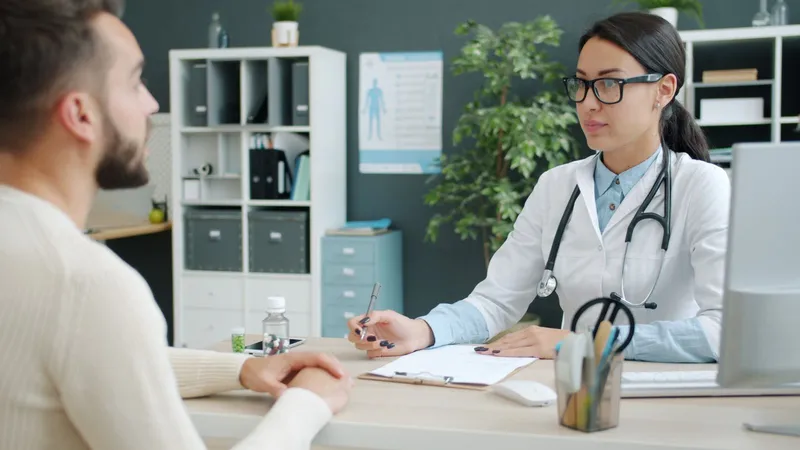 A patient and a surgeon talking across a desk during a consultation