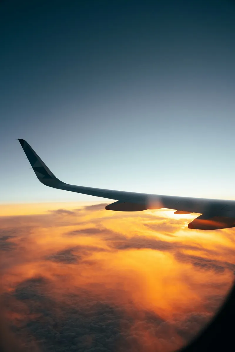 View of clouds and a wing through an aeroplane window